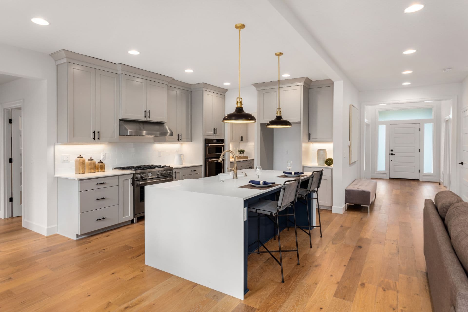 Open-plan kitchen with a white quartz island, pendant lights and hardwood floors