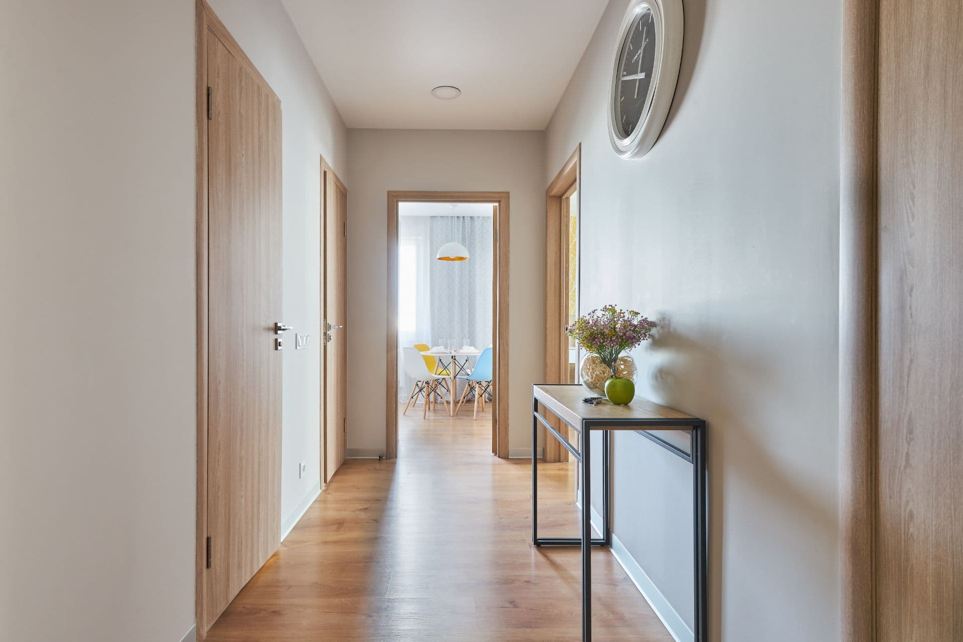 Sunlit hallway with a console table and fresh flowers, opening onto a dining room